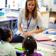 A teacher in the classroom talking to two students.
