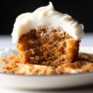 Carrot cake cupcake with cream cheese frosting on a plate.