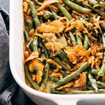 Green bean casserole in a white casserole dish with crispy fried onions on top.
