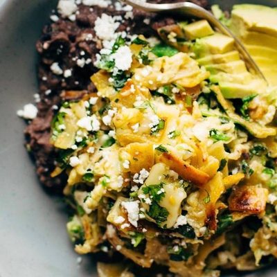 Migas in a bowl with avocado and refried black beans.