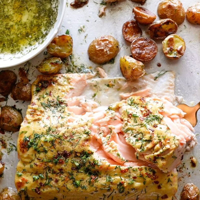 Salmon and potatoes on a sheet pan covered in dill.