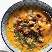 Sweet Potato Soup in a bowl with cauliflower crumbled on top.