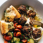 Meatballs in a bowl with a tomato salad and bread