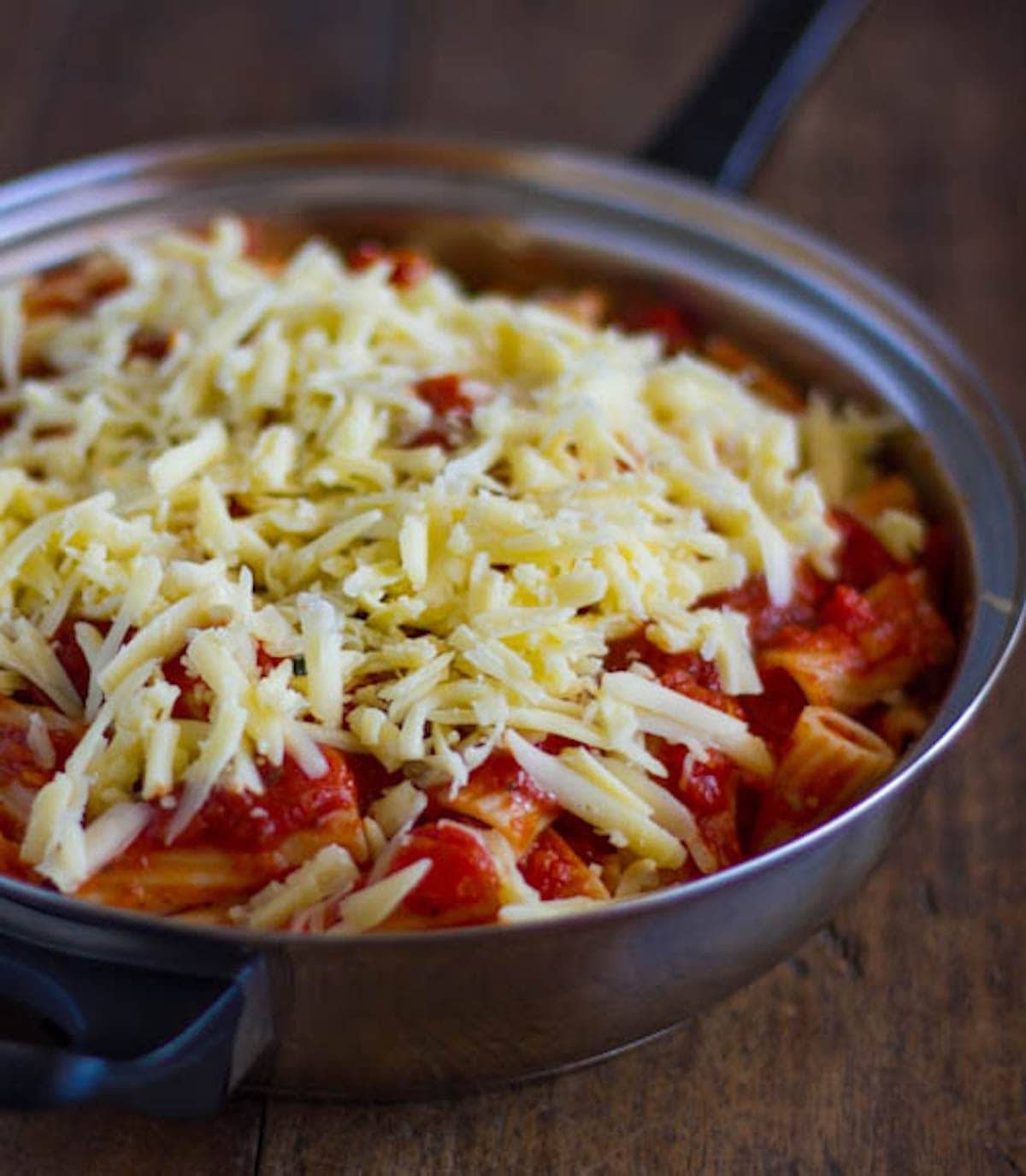 Baked caprese rigatoni with tomatoes, basil, and Mozzarella in a pan.